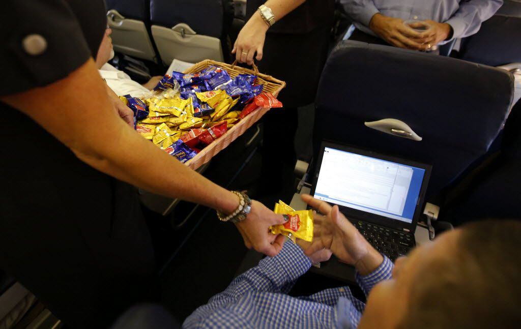 Southwest Airlines Jenni Heikkinen hands out peanuts to passengers on Southwest Airlines...