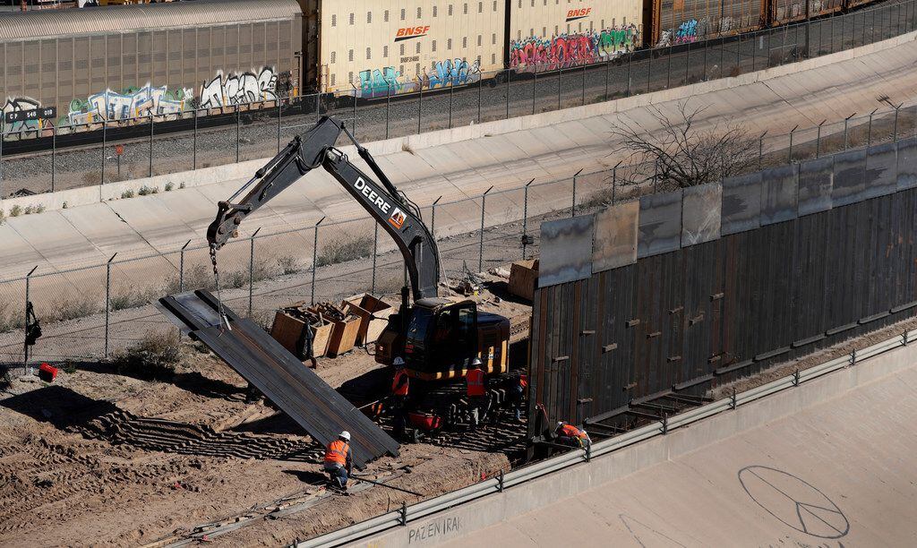 Workers on January 22 place sections of metal barrier along the U.S.-Mexico border near...