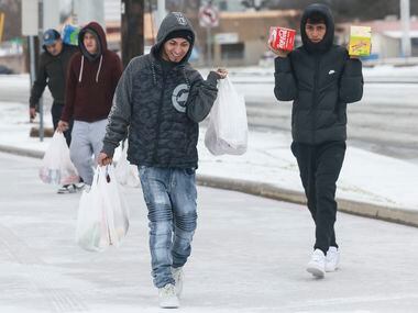 Eduardo Rojas (left) and his cousins haul groceries through the snow, Tuesday, Jan. 31,...