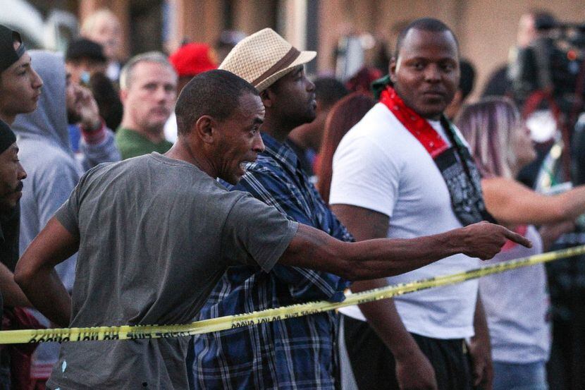 Un hombre señala a un oficial mientras que otros miran la escena donde un hombre negro fue...