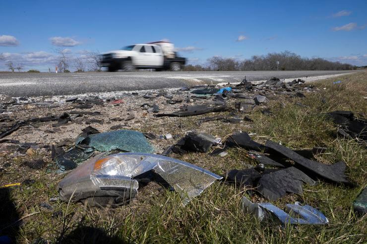 Drivers pass by debris, where six people, including two children, were killed and three...