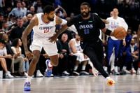 Dallas Mavericks guard Kyrie Irving (11) dribbles up court alongside LA Clippers forward...