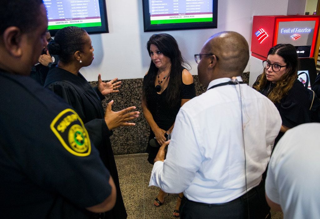 District Judge Tammy Kemp (second from left) talks with reporters in the hallway outside the jury room as potential jurors are selected for the Amber Guyger trial on Friday. The media was briefly barred from the room but later allowed inside once the crowd of potential jurors had thinned.