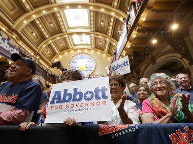 A supporter of Texas Gov. Greg Abbott uses a sign to block protesters prior to an event...