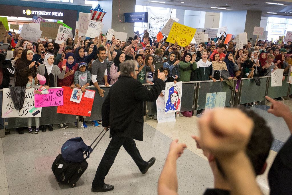 A passenger gives a thumbs up to protestors in the international arrivals hall at DFW...