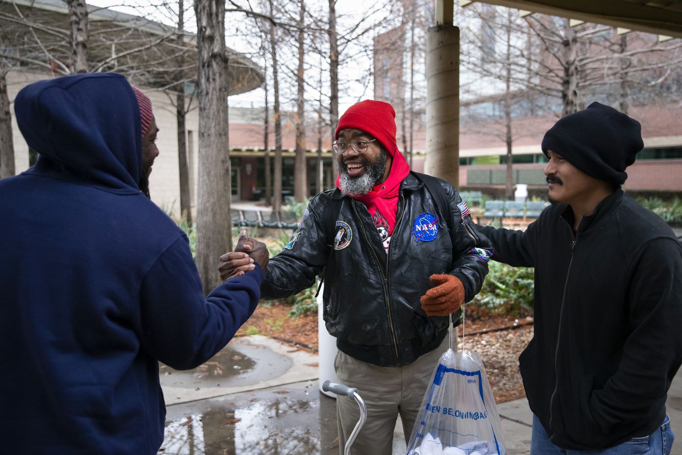 Randy greeted Rico Dukes (left) and Carlos Peña while walking around The Bridge Homeless Recovery Center in Dallas on Jan. 11, 2020. Randy lived at The Bridge for over a year while he navigated social services that could help him afford and secure a two-bedroom apartment with his $1,400-a-month disability income.