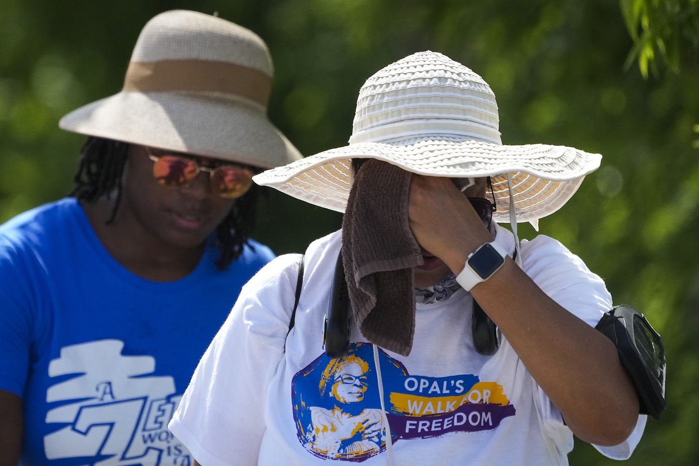 Walkers wipe away sweat during the 2022 Opal's Walk for Freedom on Saturday, June 18, 2022,...