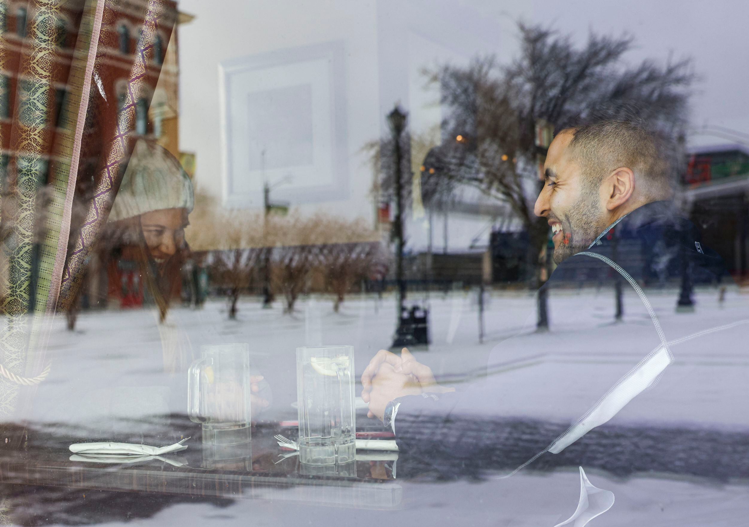 Part of snow-covered downtown Frisco is reflected on a window of a Best Thai restaurant as...