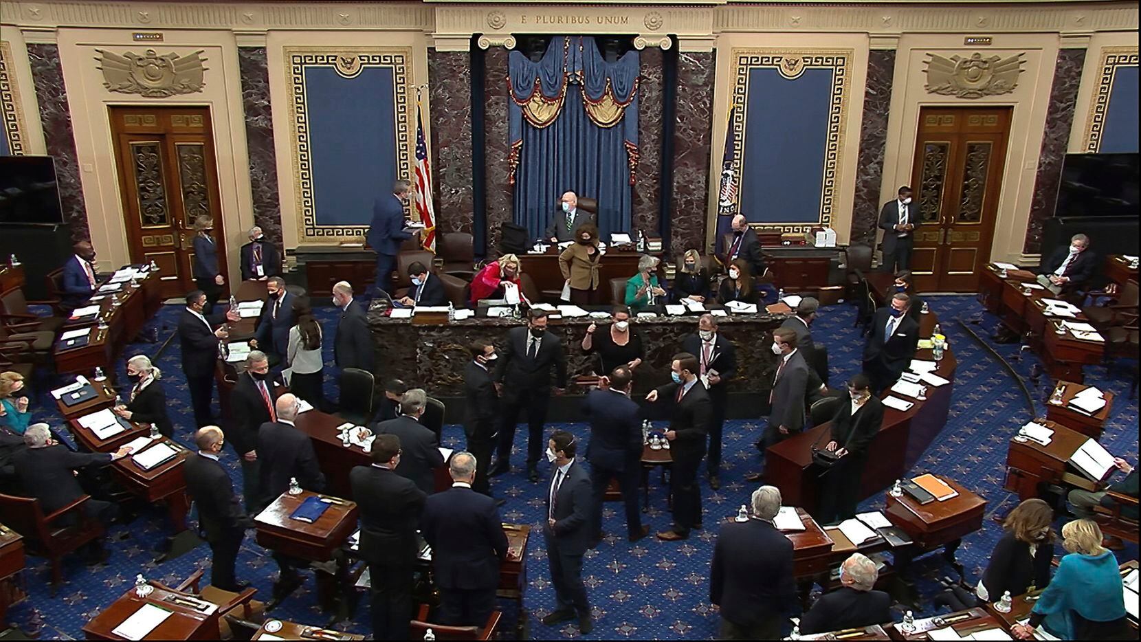 In this image from video, senators, staff and attorney's talk after a point of order was made by Sen. Mike Lee, R-Utah, during closing arguments in the second impeachment trial of former President Donald Trump in the Senate at the U.S. Capitol in Washington, Saturday, Feb. 13, 2021. (Senate Television via AP)