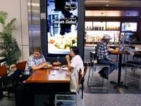 Passengers enjoy lunch with their dog at Bar Louie, one of the restaurants owned by Paradies...