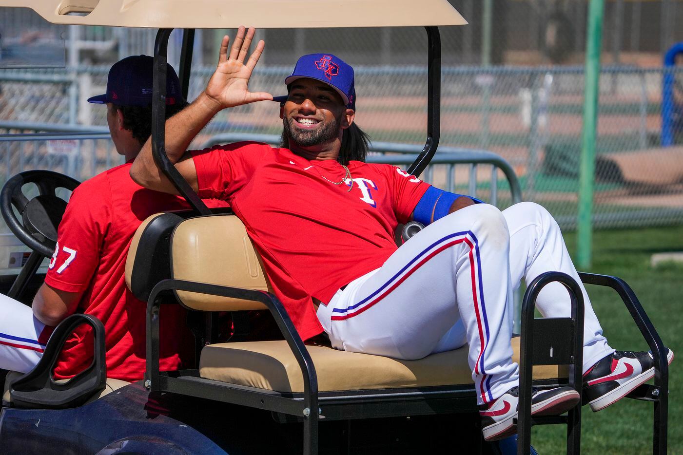 Texas Rangers infielder Ezequiel Duran waves to fans as he rides in a golf cart driven by...