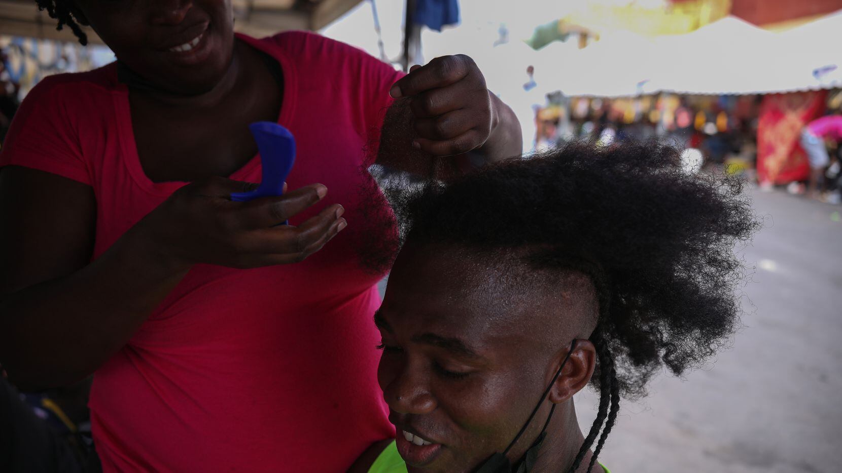 Jean Rodmique, 32, from Haiti, sits on a chair while his wife braids his hair, Wednesday,...