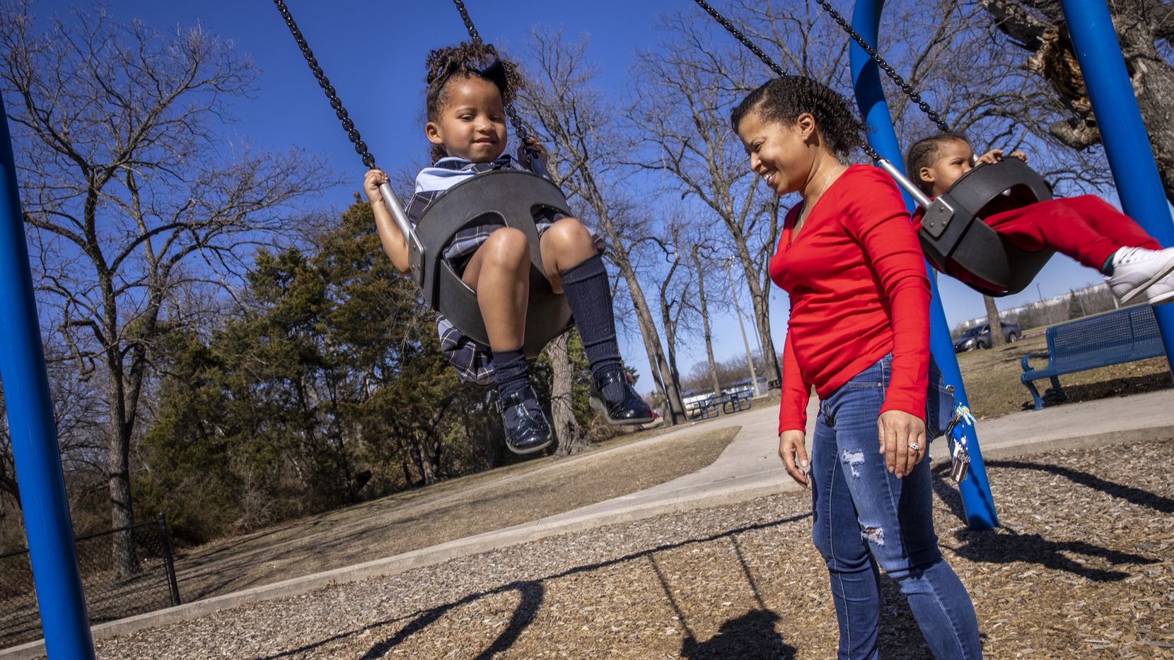Marchelle Simpson (center) pushes her children, Kyla, 4 (left) and Kyre, 2, on the swings at...