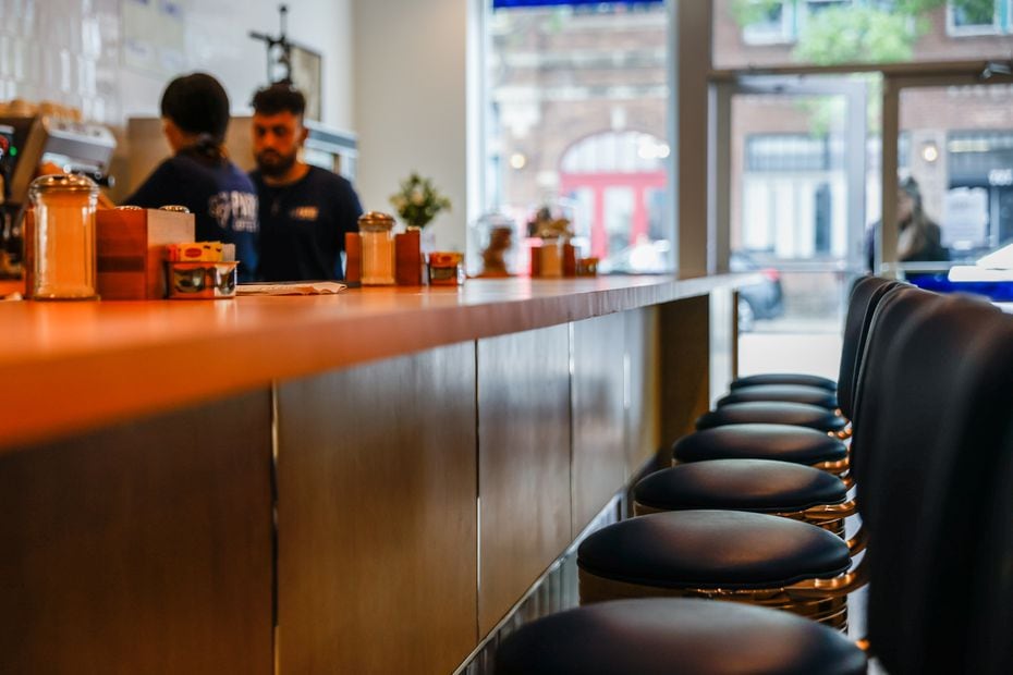 Paris Coffee Shop has navy swivel chairs that sit at a bright orange counter. The building...