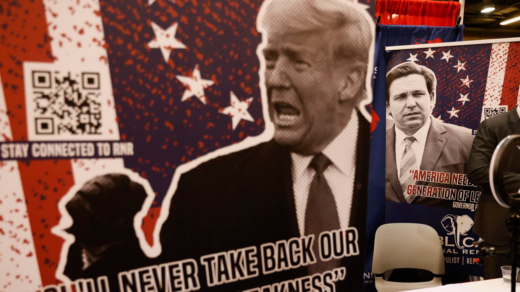 A poster of former President Donald Trump and Governor of Florida Ron DeSantis at a booth...