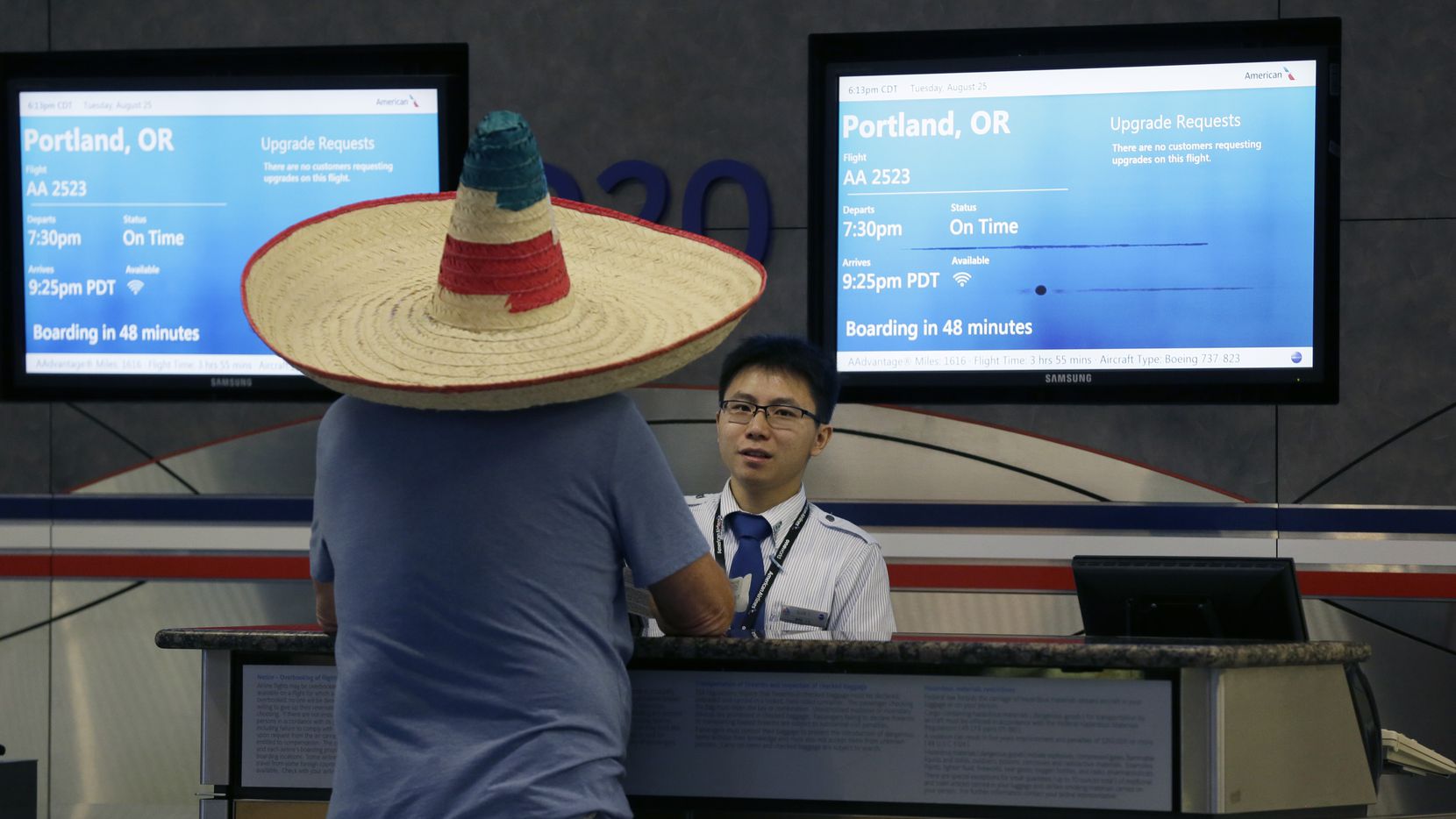 A passenger wearing a sombrero checks with a flight gate agent at Dallas/Fort Worth...