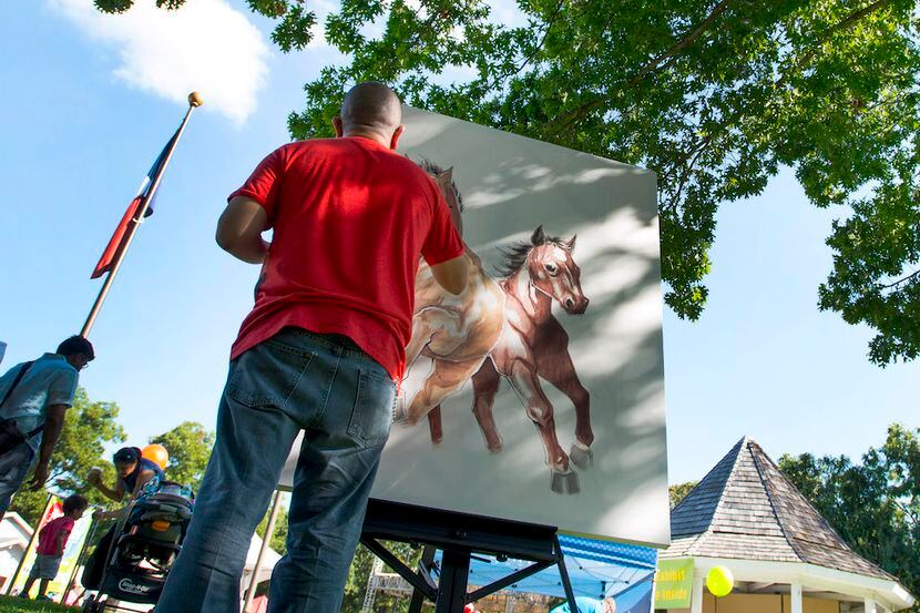 Artist Miguel Sotelo works on a painting during the Main Street Festival in Irving.