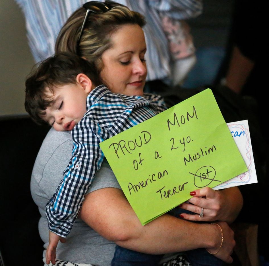 Casey Sabti and her two-year-old son Laith of Dallas take a break from the protest at DFW...