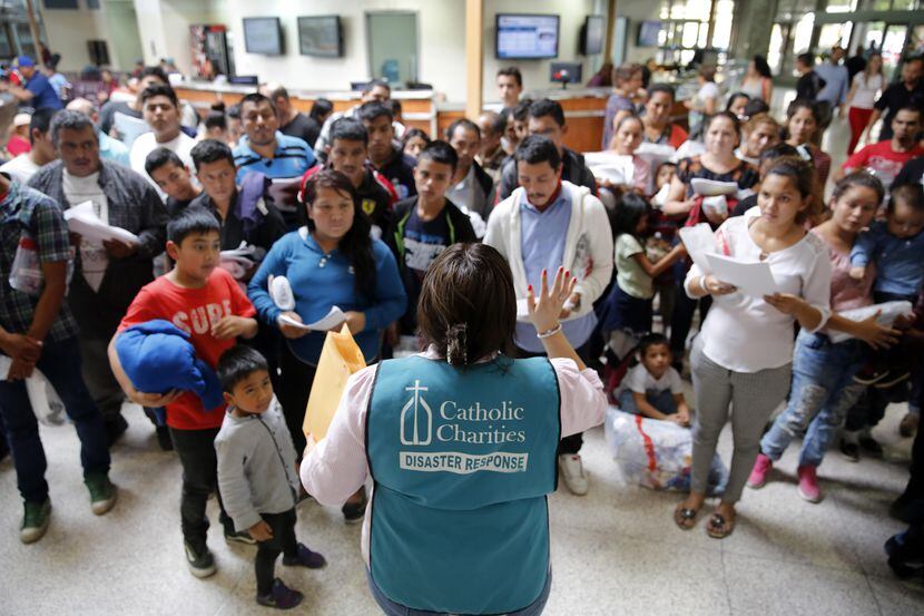 Un integrante de Caridades Católicas da instrucciones a un grupo de inmigrantes en una...