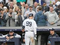 Fans cheer New York Yankees' Aaron Judge walks to the dugout after striking out in the...