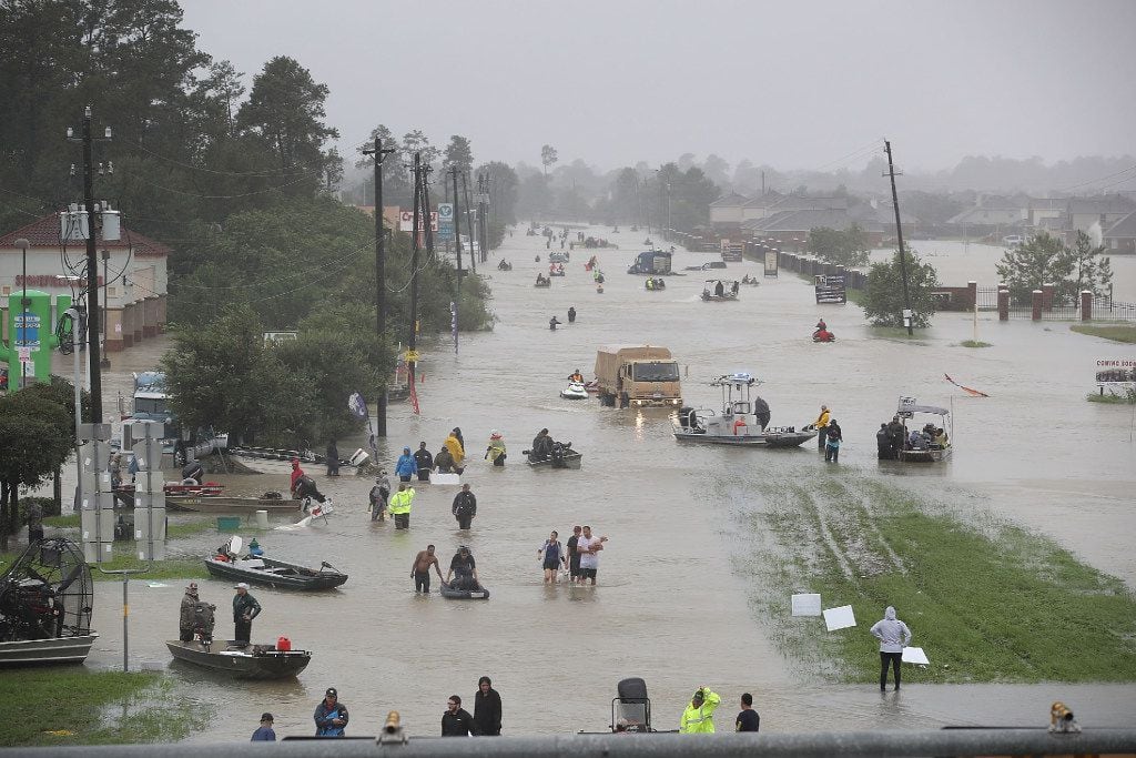 People walk down a flooded street as they evacuate their homes after the area was inundated...
