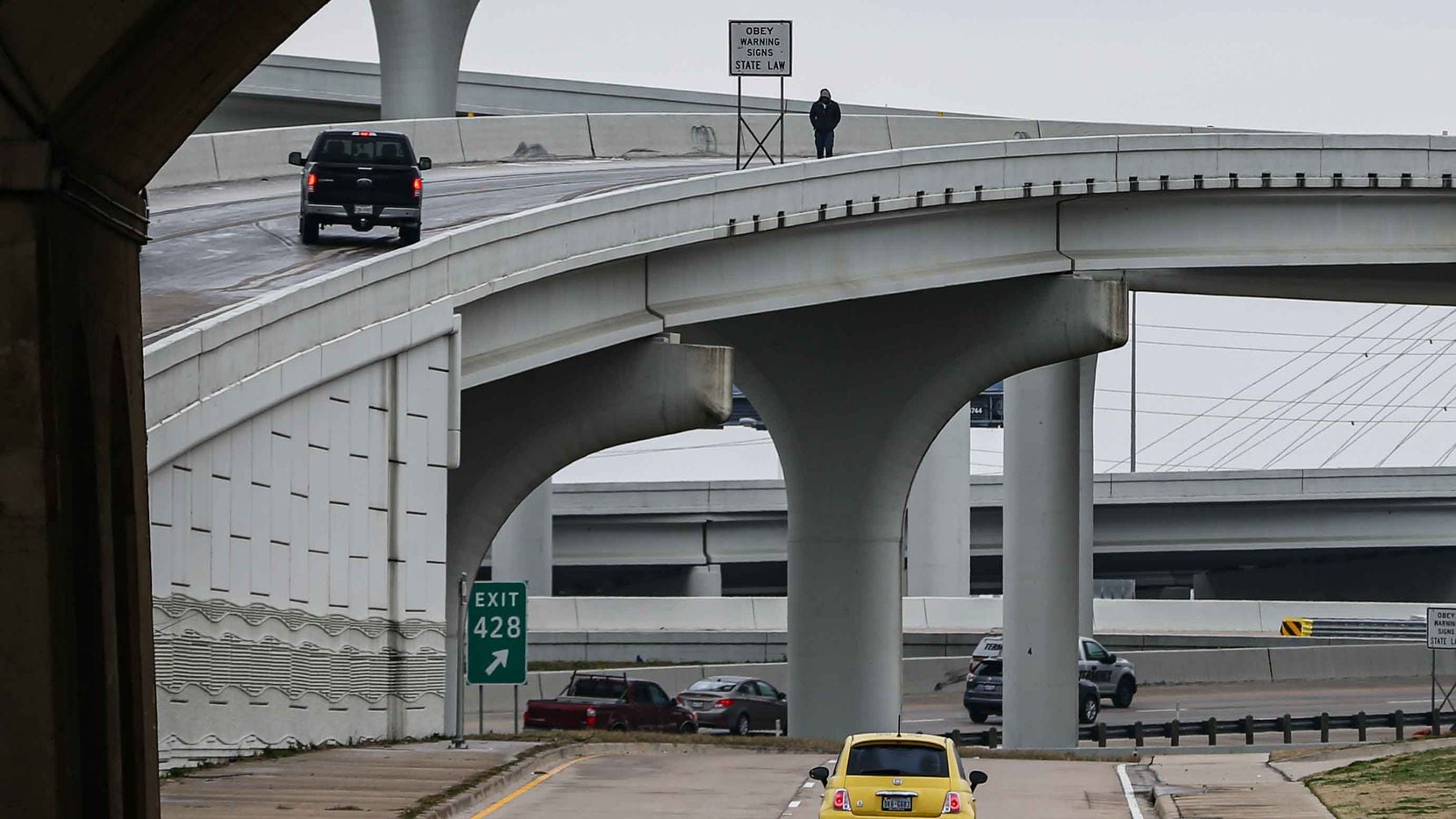 A person stands outside their vehicle as the traffic stops at the I-30 west to I-30 east...