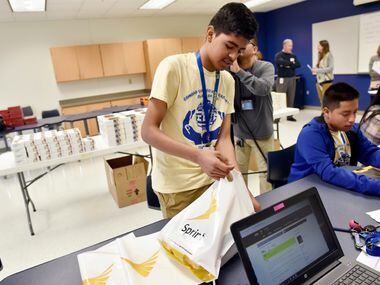 Jesus Manqueros (left), 14, packs the free Sprint tablet he received through the Sprint...