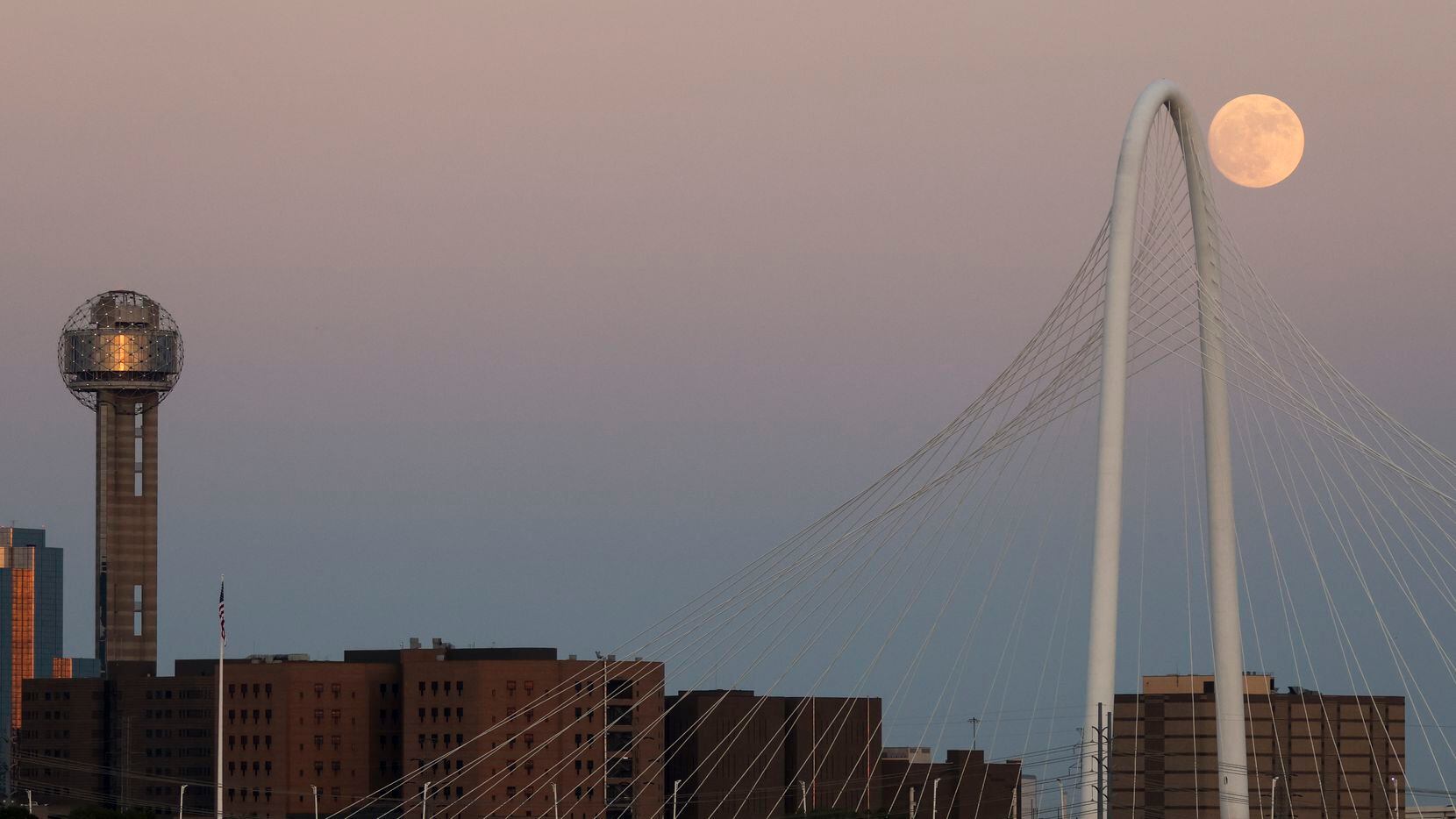 The moon rises next to the Margaret Hunt Hill Bridge and Reunion Tower on Tuesday.