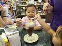 In this DMN file photo, Sophia Lau shares her ice cream treat around its 100th anniversary in 2012. In 2022, the owners of The Charles and Sister have plans to open a restaurant in place of the former pharmacy and milkshake shop.