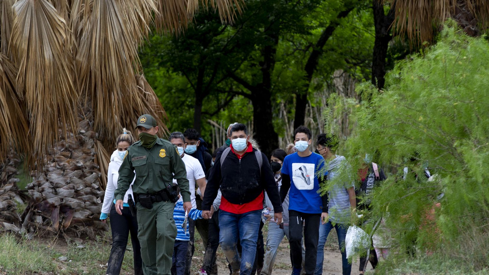 A U.S. Customs and Border Patrol agent leads a group of migrants, mostly from Venezuela, out...