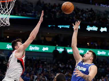 Dallas Mavericks guard Luka Doncic (77) floats a shot over the outstretched arm of Portland...
