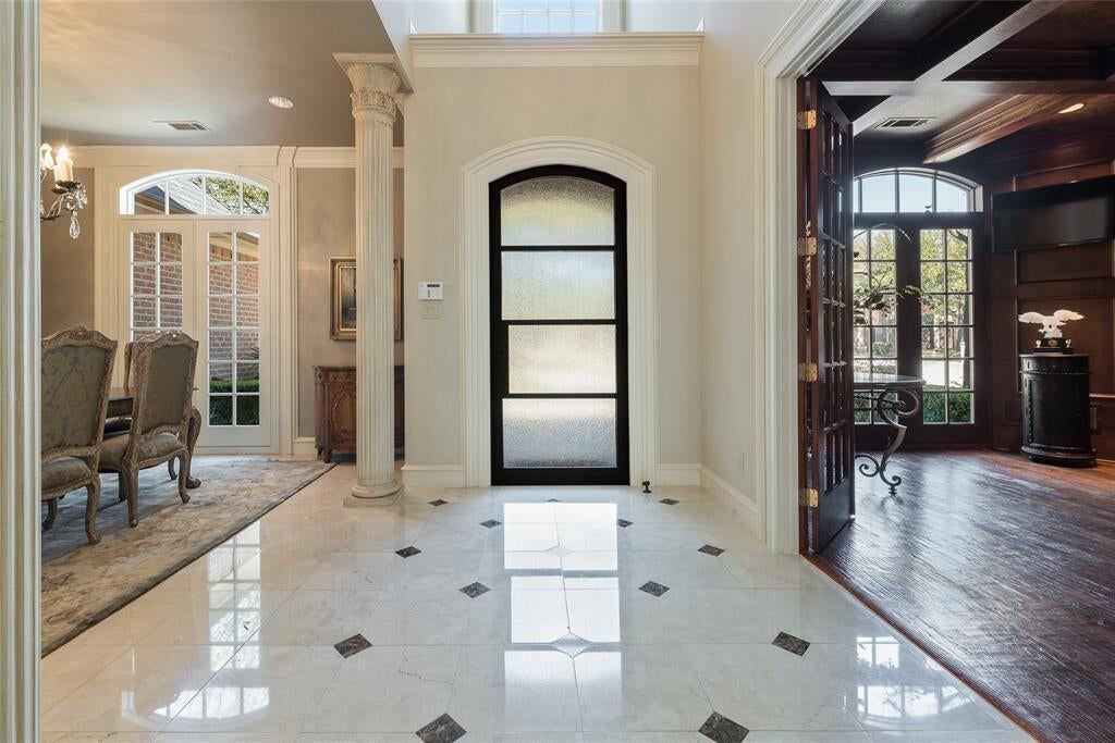 The front door is flanked by four fluted stone columns with two more Corinthian columns...