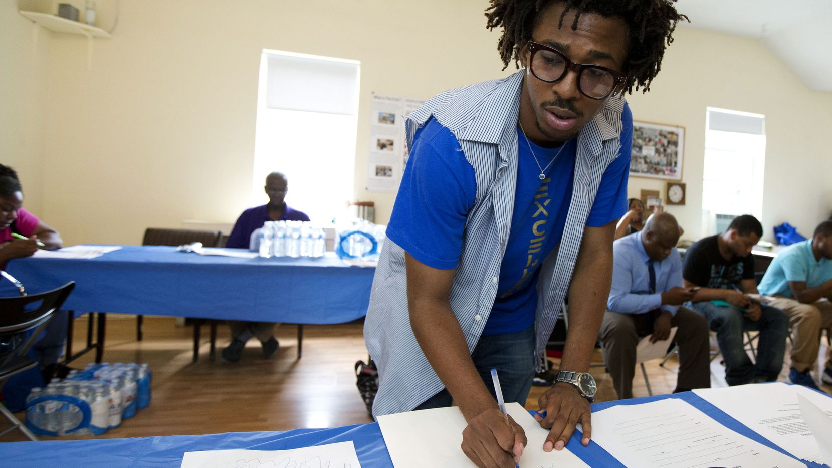 In this Wednesday, July 31, 2013, file photo, Americorps volunteer John Harris III, who is helping to coordinate a jobs fair program, fills out documents for job seekers in Washington.