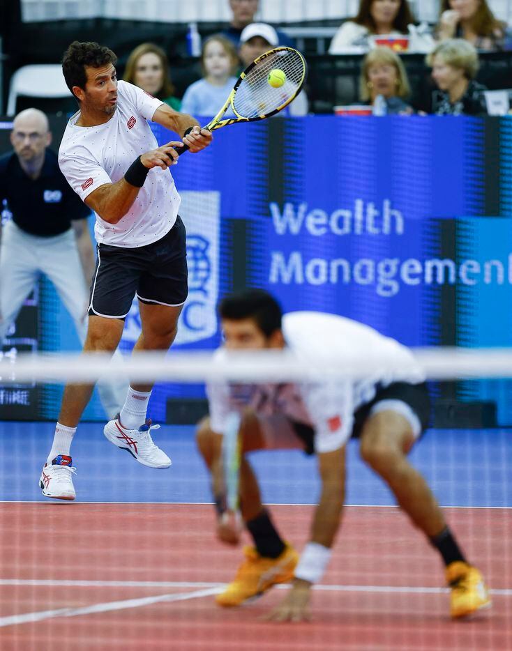 Jean-Julien Rojer, returns the ball as his teammate Marcelo Arevalo kneels during the...