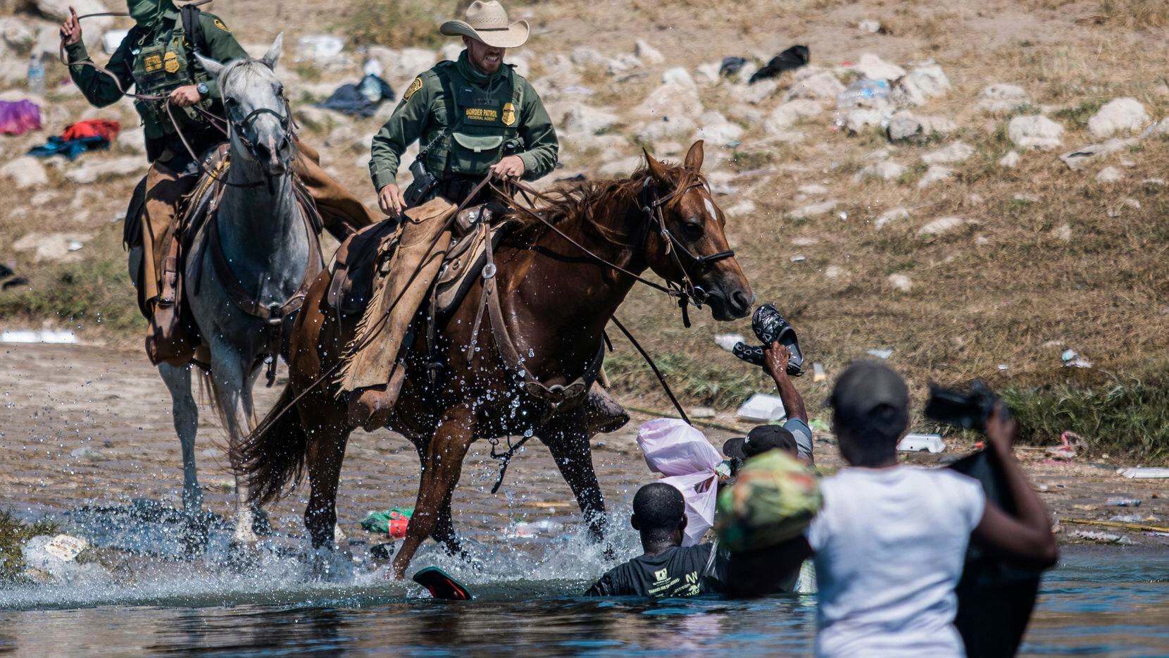 FILE - Mounted U.S. Border Patrol agents attempt to contain migrants as they cross the Rio...
