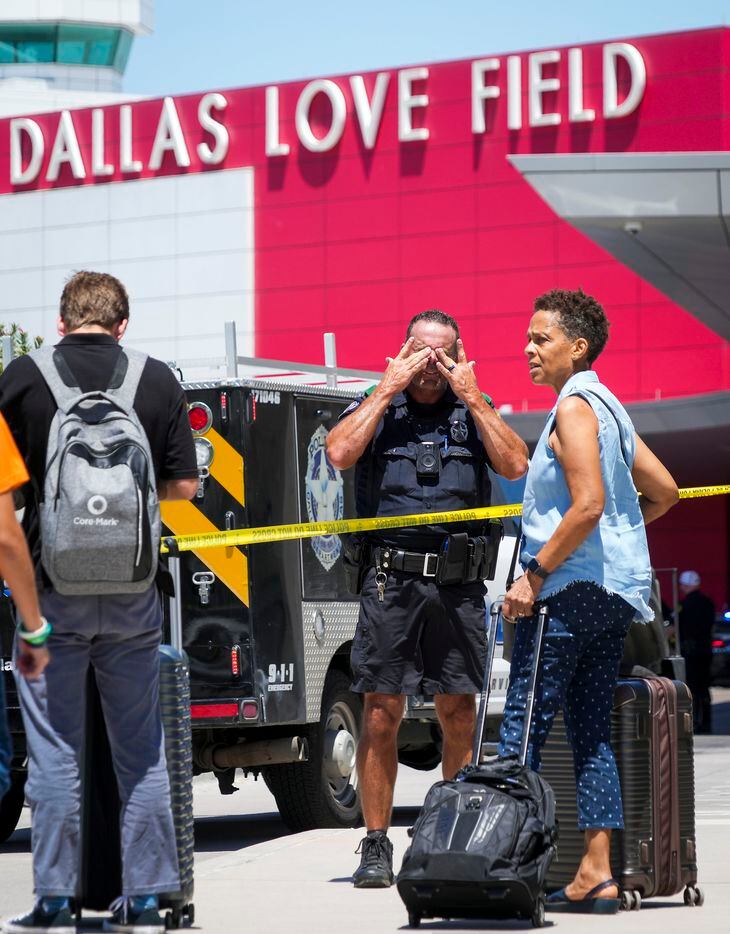 A Dallas police officer wipes sweat from his eyes as he directs passengers away from the...