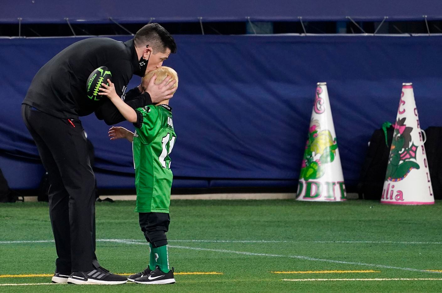 Southlake Carroll head coach Riley Dodge kisses his son Tate, 5, on the sidelines before the Class 6A Division I state football championship game against Austin Westlake, coached by his father Todd Dodge, at AT&T Stadium on Saturday, Jan. 16, 2021, in Arlington, Texas. (Smiley N. Pool/The Dallas Morning News)