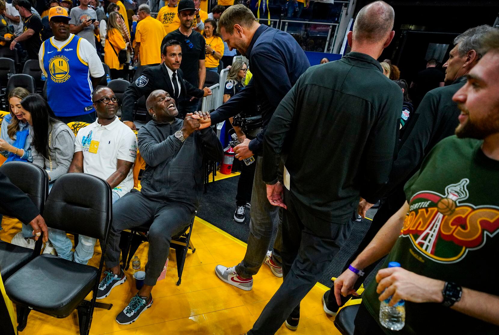 Dirk Nowitzki shakes hands with Gary Payton (seated) after the Golden State Warriors victory...