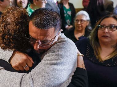 Surrounded by family members, Martin Santillan (center) embraces his friend Andrea Alvarado...