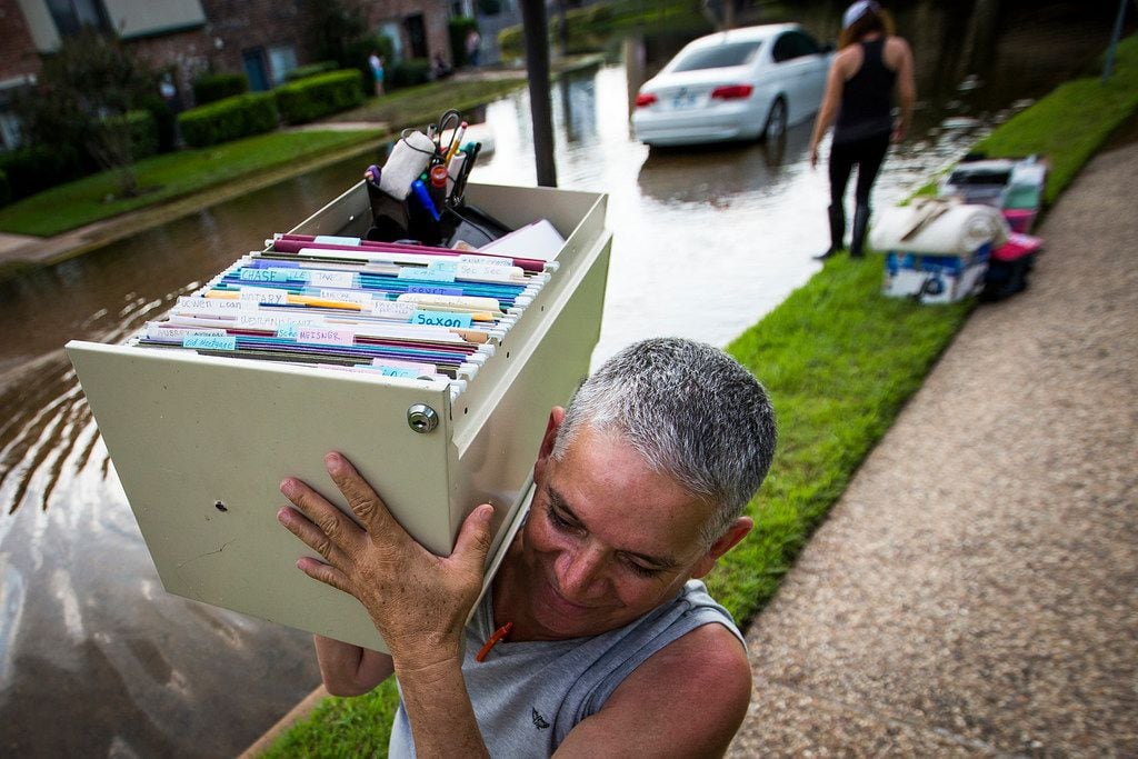 Robin Cardona retrieves belongings from his west Houston apartment through flood water from...
