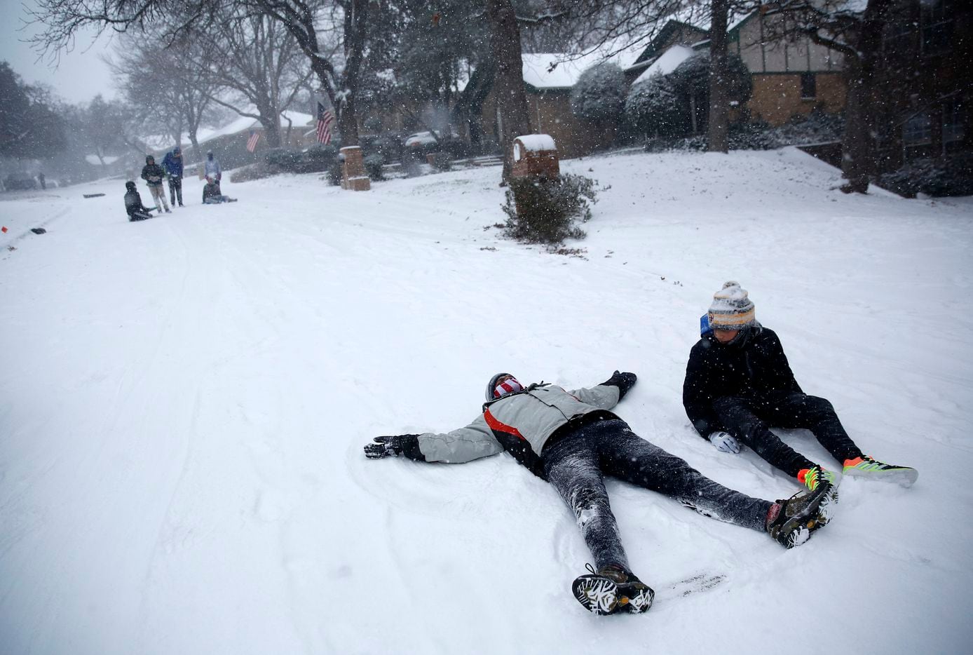 Sayan Mandal (left) and Ryan Lane take a break from sledding to make snow angels on a steep...