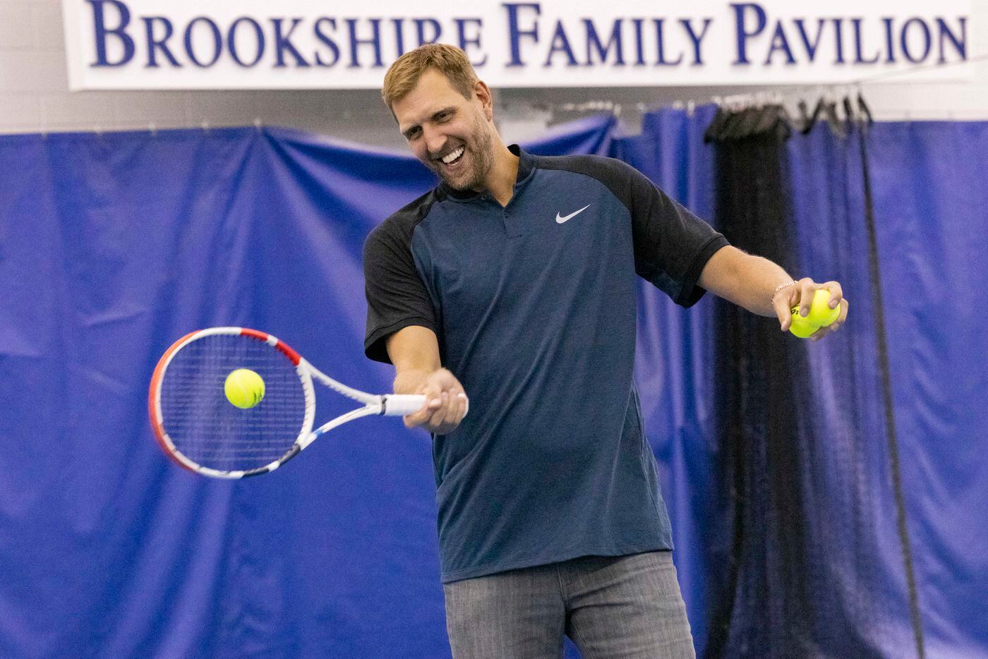 Dallas Mavericks star Dirk Nowitzki hits the tennis ball to John Isner, 15-Time ATP Tour...