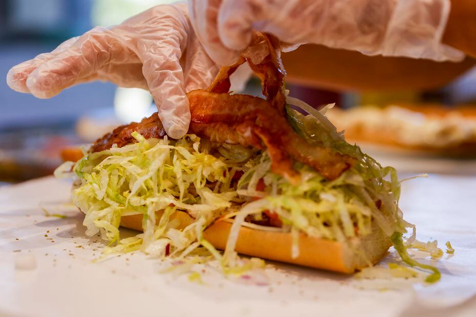 Bacon is added to a ham, turkey and provolone sandwich at Great American Hero’s new location...
