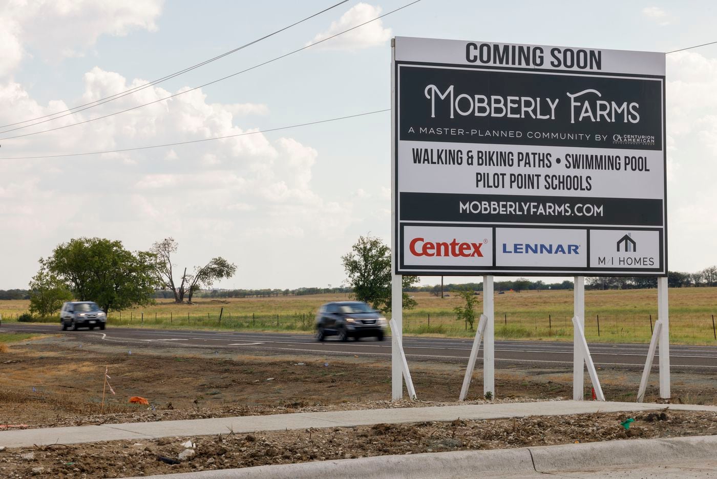 Cars drive past the Mobberly Farms development in Pilot Point on Aug. 12.