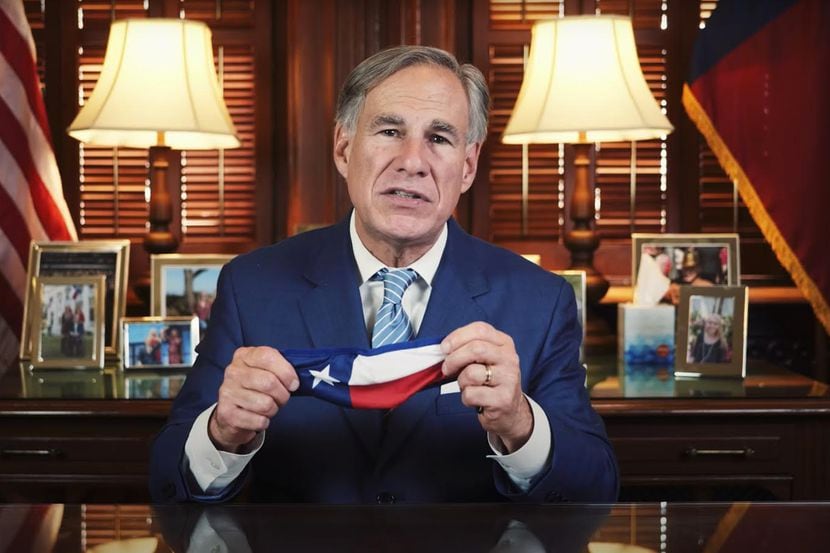 Texas Governor Greg Abbott holds up a mask during his state mandate that requires all Texans...