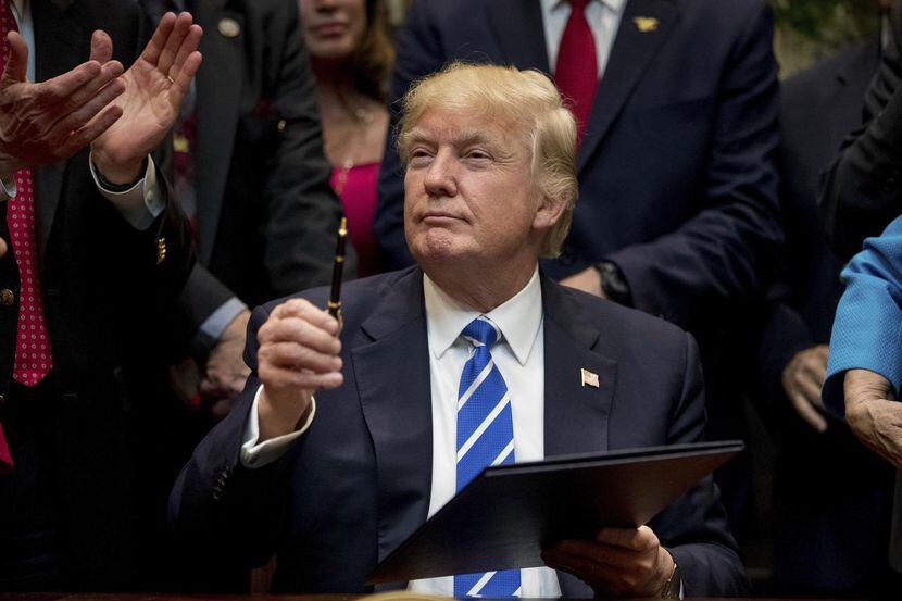 El presidente de Estados Unidos, Donald Trump, sostiene un bolígrafo para firmar una ley en...