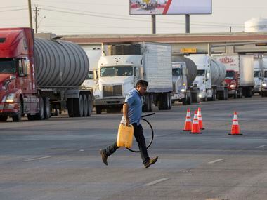 Jesus Hernandez runs across S Cage Blvd after refueling his driver with diesel in the line...