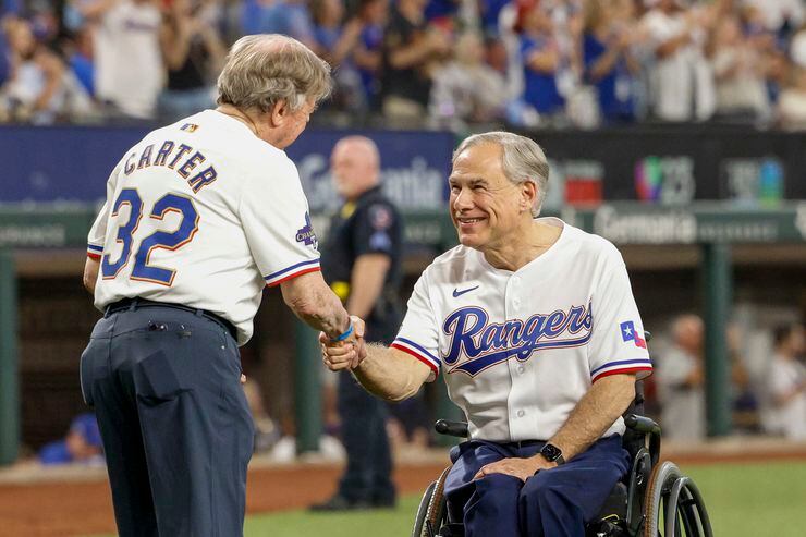 Texas governor Greg Abbott greets Texas Rangers fan Michael Carter before Carter throws out...