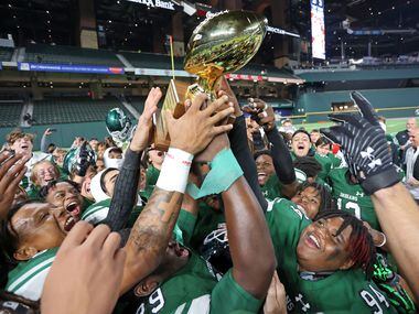 Waxahachie high players mob a trophy at the end of high school football game win over...