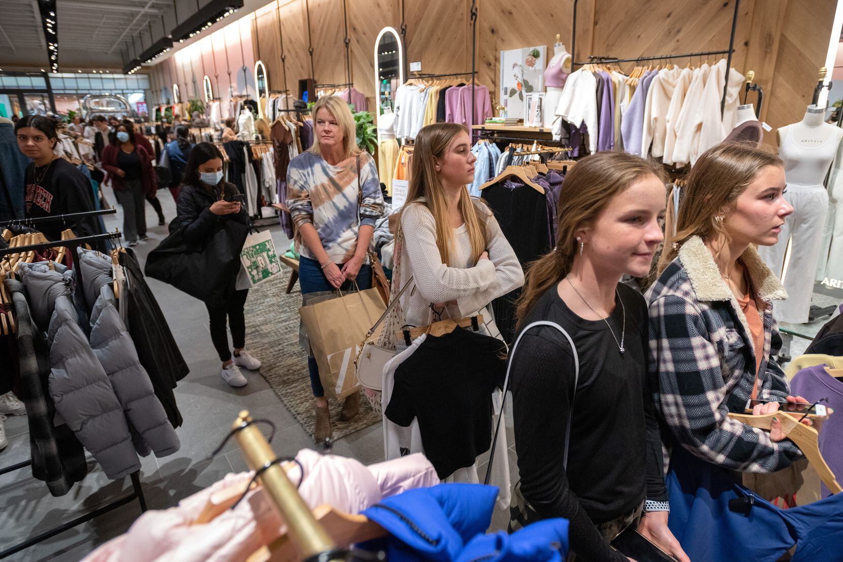 Brooke Baker, 16, center, Brooklyn Brothers, 16, right, and Micah Tuthill, 16, far-right, wait in line with other shoppers to pay for merchandise inside of Aritzia on Black Friday at NorthPark Center in Dallas, on Friday, Nov. 26, 2021. 